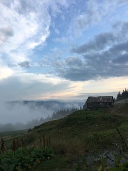 山坡上的木制小屋笼罩在薄雾中，天空显得格外戏剧性