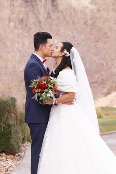 Bride and groom sharing a romantic kiss outdoors, highlighting love and commitment.