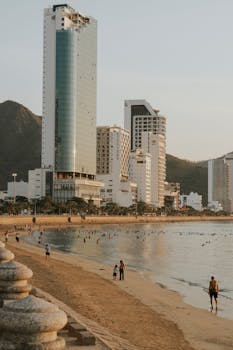A bustling beachfront with tall buildings and lively shore at sunset.