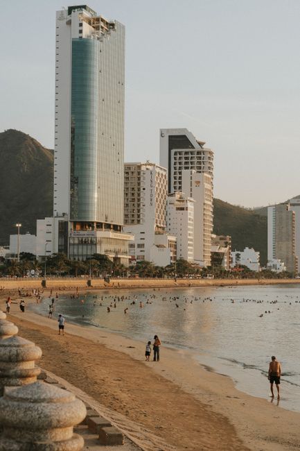 A bustling beachfront with tall buildings and lively shore at sunset.