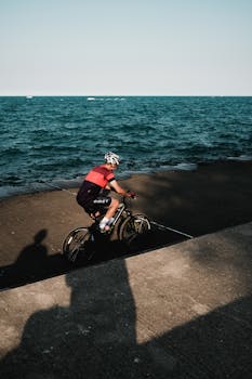 A cyclist in action on a sunny day by a lakeside path, capturing a moment of outdoor recreation.