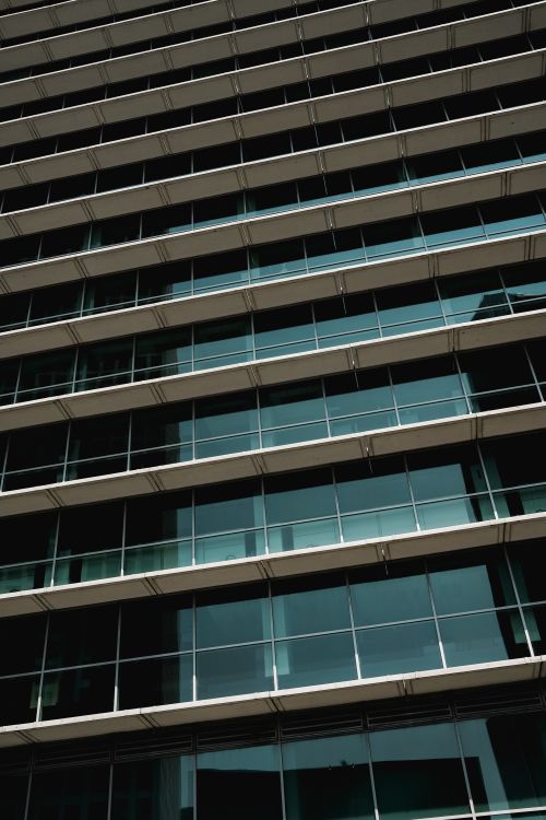 Free Angled photograph of a contemporary glass facade skyscraper highlighting reflections. Stock Photo