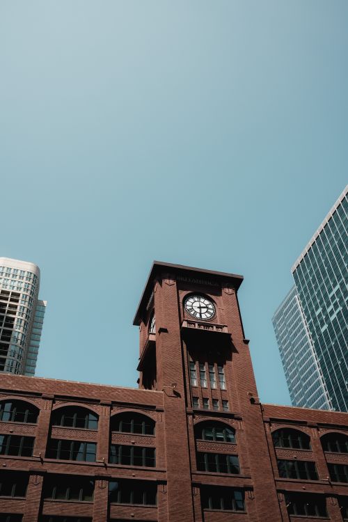 Free A classic Chicago clock tower stands prominently amidst modern skyscrapers under a clear blue sky. Stock Photo