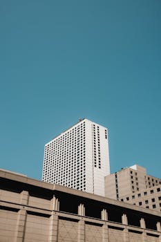 City skyscrapers rise tall against a clear blue sky, showcasing urban architectural design.