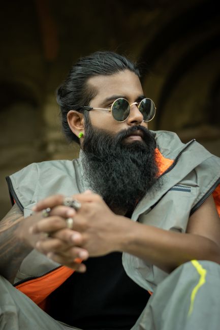 A stylish man with a full beard and sunglasses in an urban setting in Delhi.