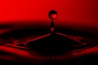 特写图像捕捉了水滴在生动的红色背景上飞溅的戏剧性瞬间