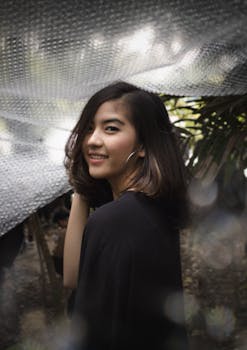 一位微笑女子的肖像，在户外以泡沫包装为背景，展现休闲时尚与自然之美