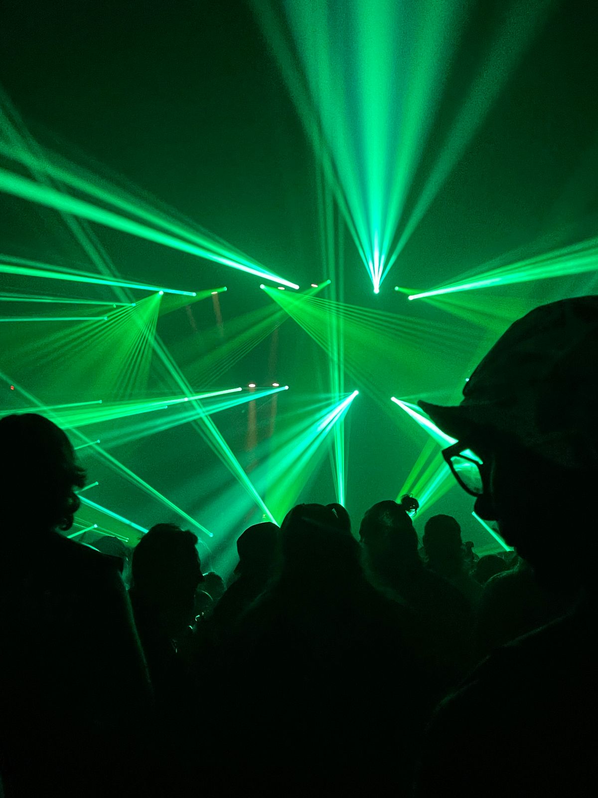 Green laser beams cutting through haze at a live laser show
