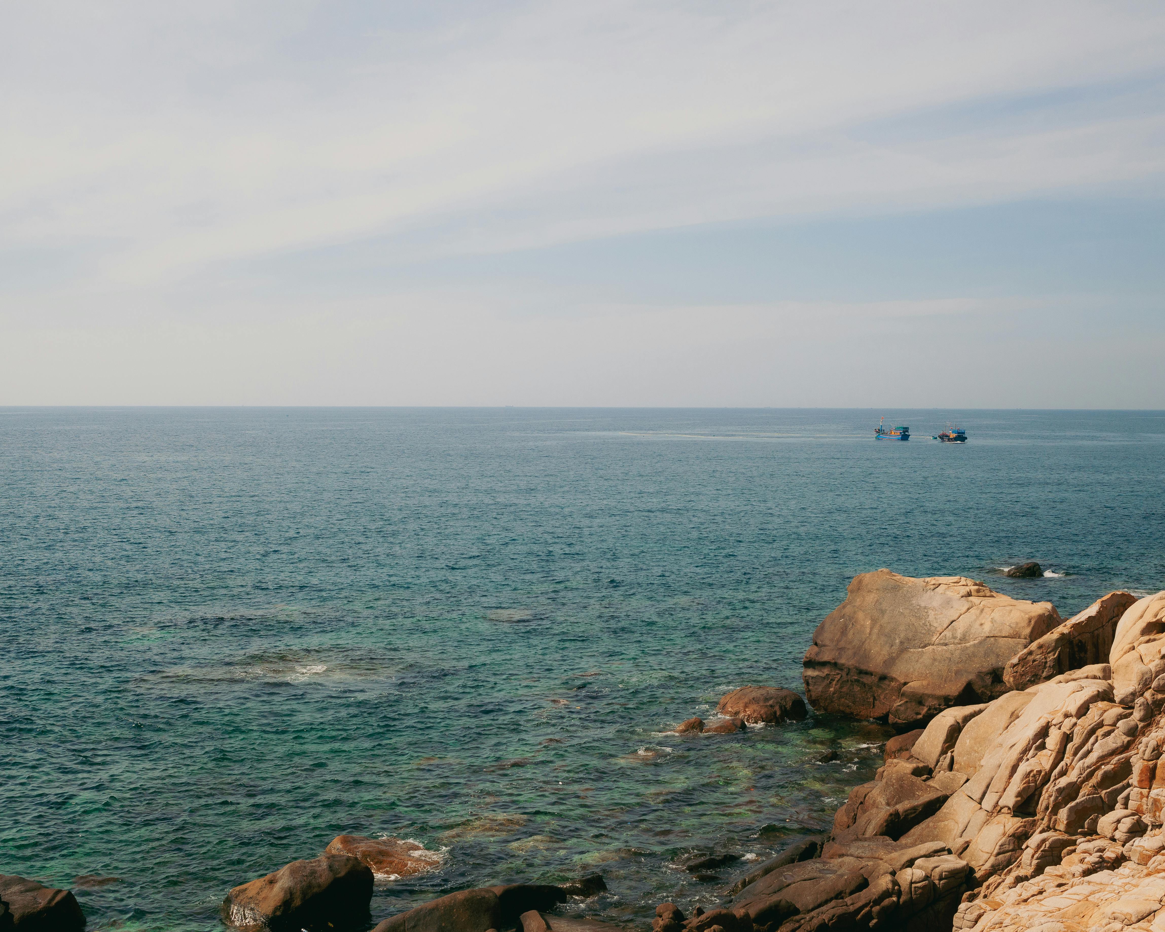 Serene view of the ocean and rocky shore in Phan Rang–Tháp Chàm, Vietnam, under a clear sky.
