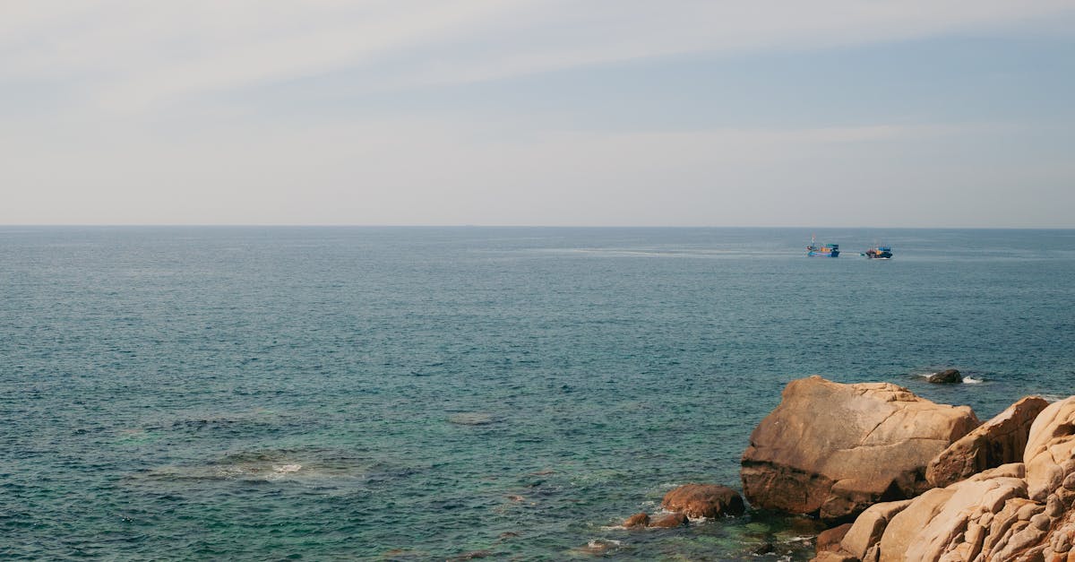 Serene view of the ocean and rocky shore in Phan Rang–Tháp Chàm, Vietnam, under a clear sky.
