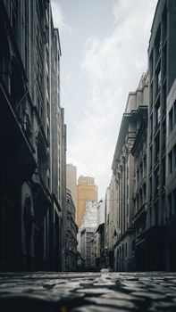 A serene urban alleyway framed by tall buildings under a cloudy sky, showcasing architectural beauty.