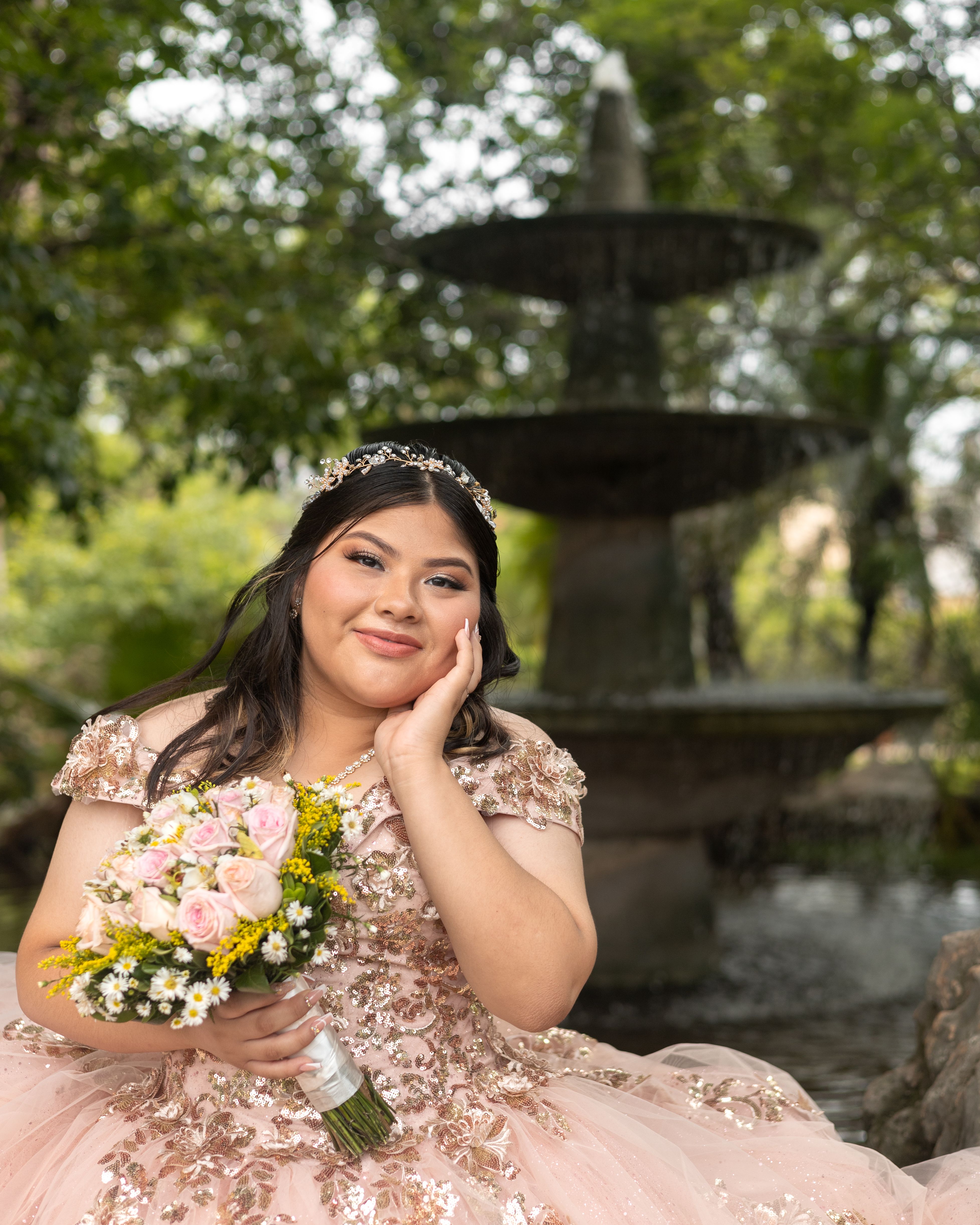 Beautiful quinceañera posing with bouquet in Mérida, Mexico park.