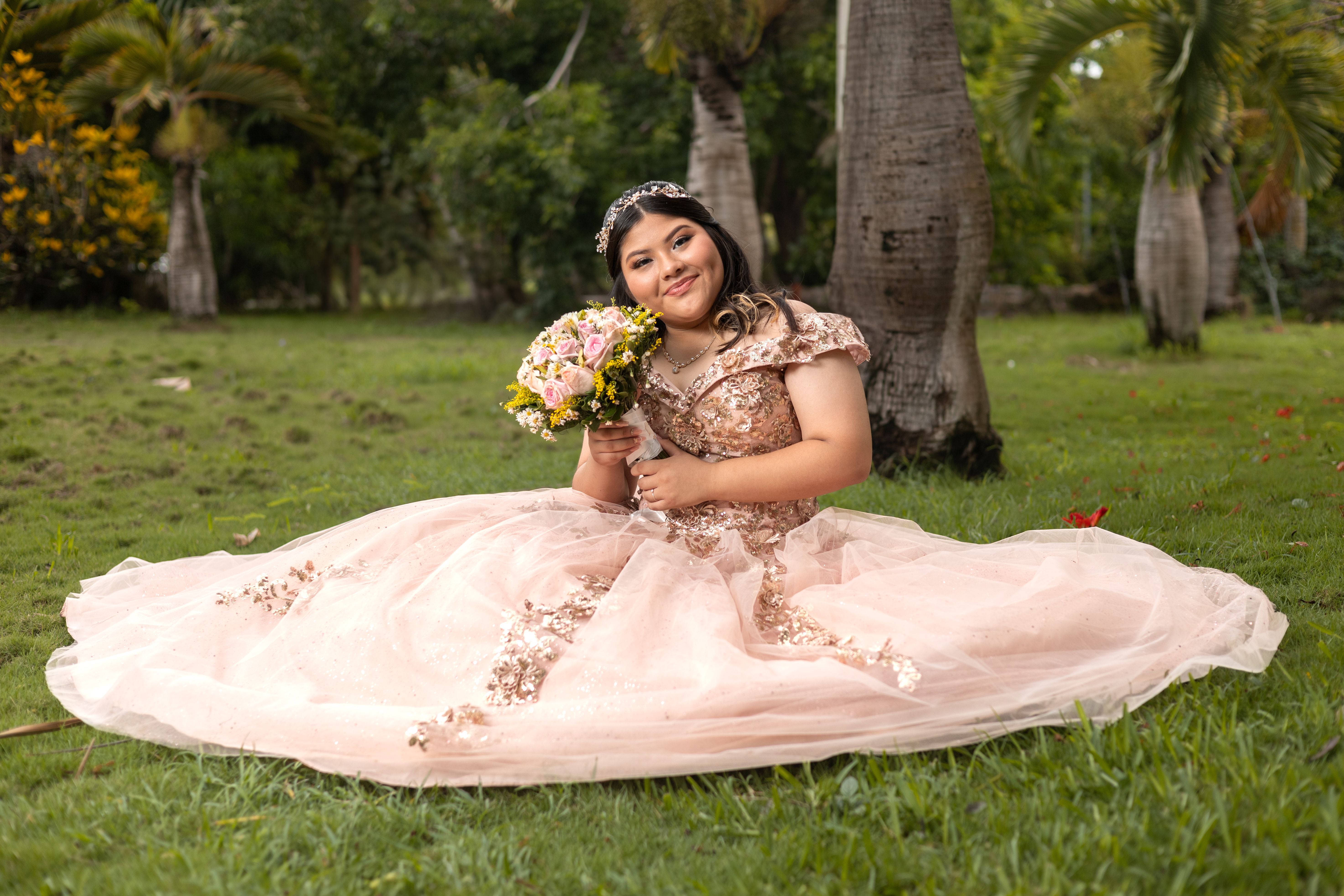 A young woman in a beautiful dress celebrates her quinceañera outdoors in a Mérida park.