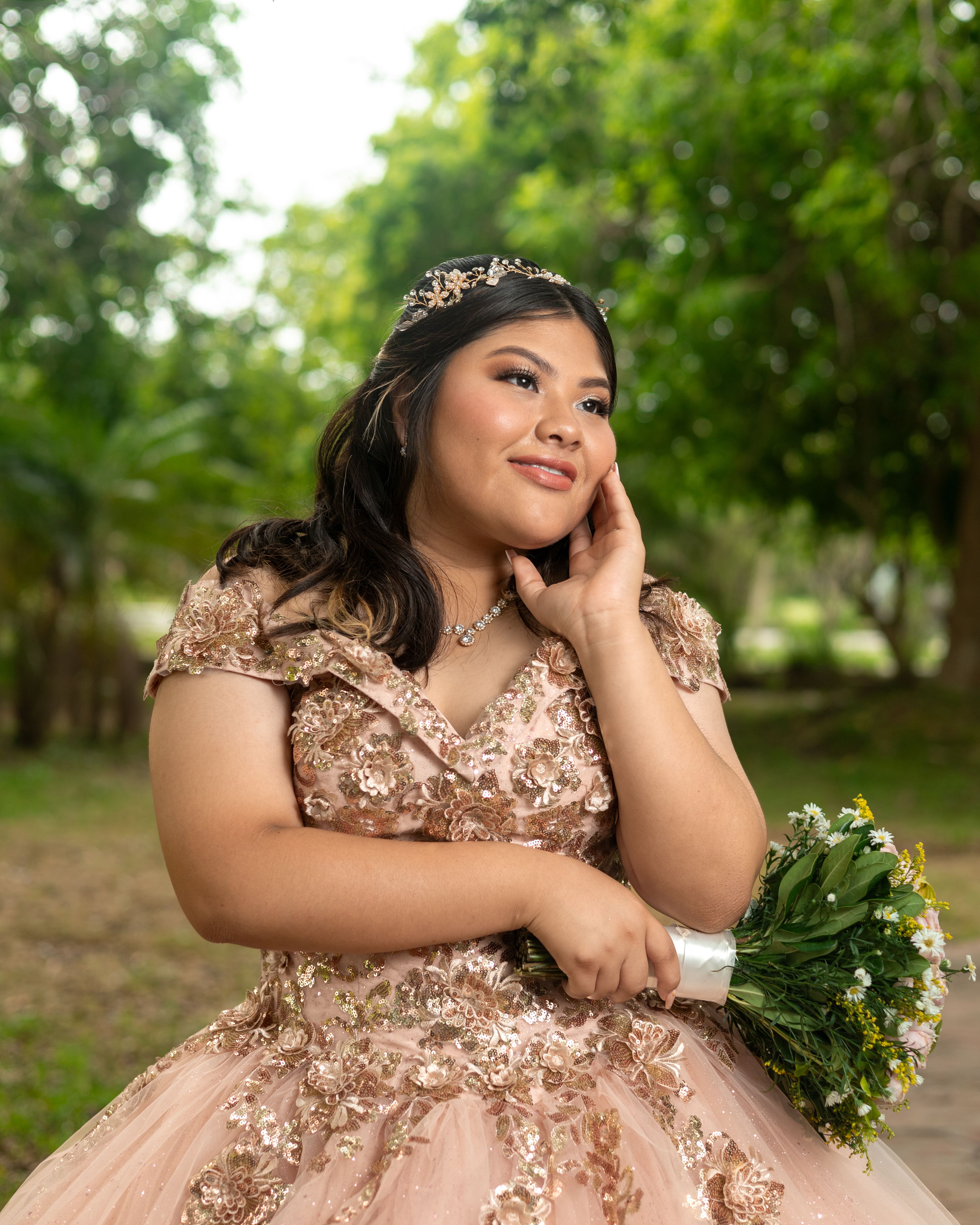 Stunning quinceañera portrait in floral gown outdoors in Mérida's lush park setting.