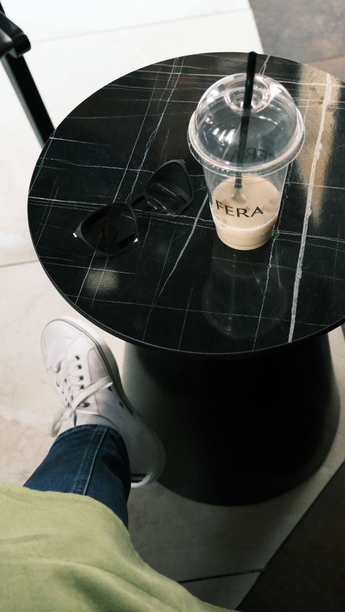 Free A chic cafe setting with a marble table, sunglasses, cold coffee, and stylish sneakers. Stock Photo