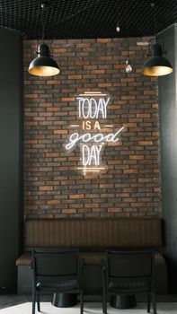 Contemporary room interior with a neon sign on a brick wall, emphasizing style and positivity.