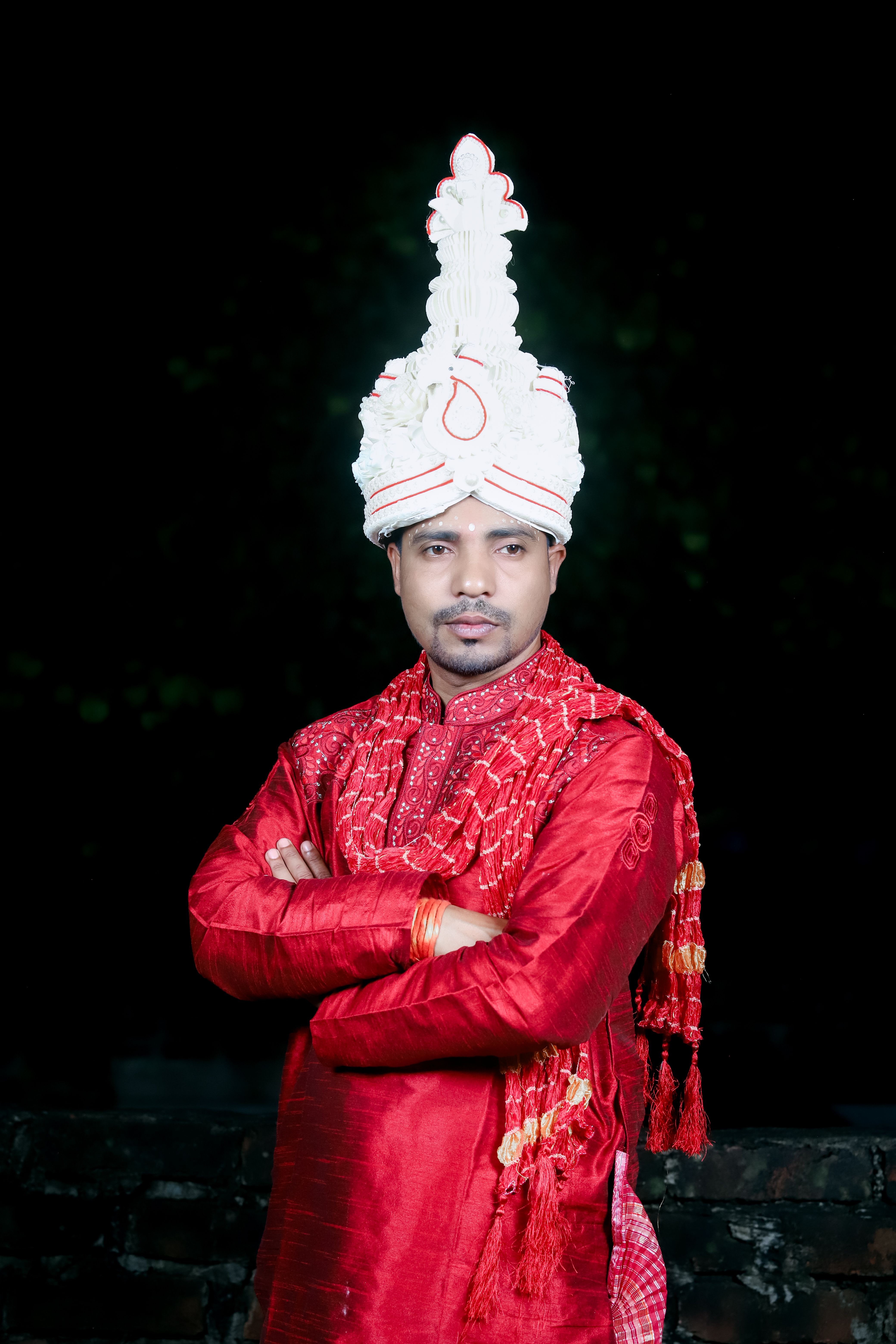 A portrait of a man in traditional festive attire with ornate headwear.