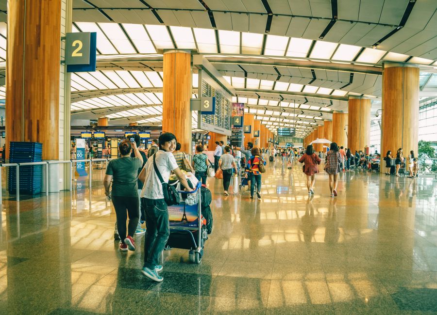 Travelers bustling through Singapore Changi Airport terminal, highlighting the dynamic and vibrant atmosphere of international travel.