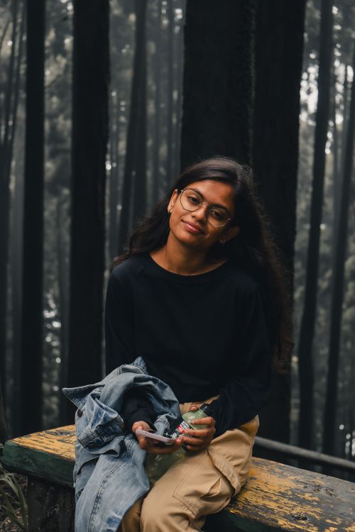 Free Woman sitting on a bench in a serene forest setting, enjoying a tranquil moment. Stock Photo