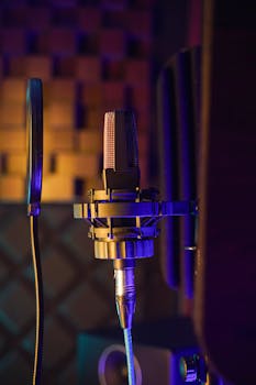 Close-up of a studio microphone with pop filter under vibrant lighting. Ideal for music production and podcast setups.