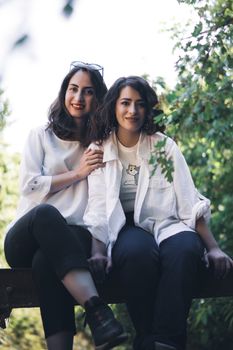 Two women sitting together outdoors, smiling and enjoying the natural surroundings.