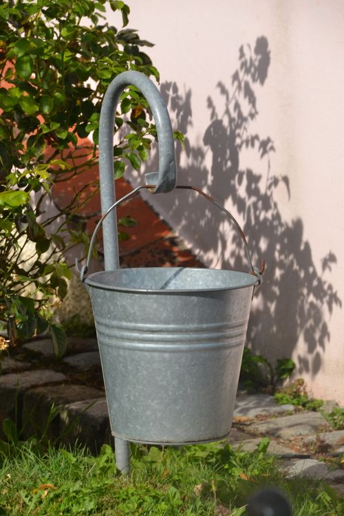 Galvanized metal bucket hanging in a sunny garden — photo by David C Murray on Pexels