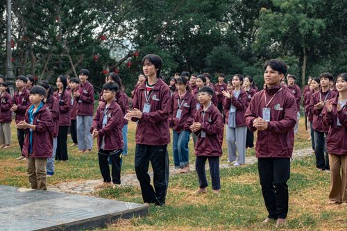 Free A large group of young people engaging in an outdoor group activity, wearing matching maroon jackets. Stock Photo