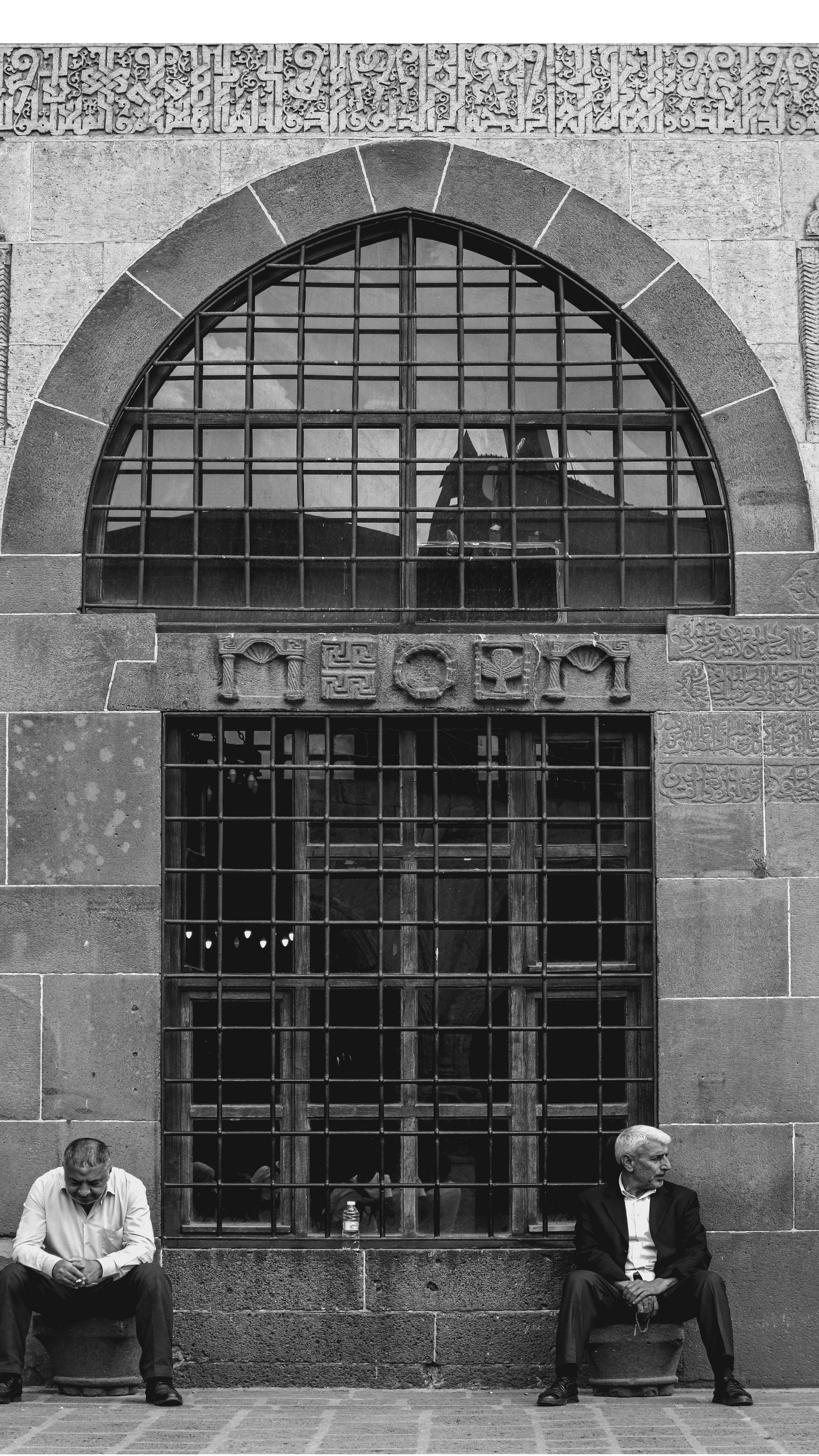 Two men sit on a bench outside of a building · Free Stock Photo