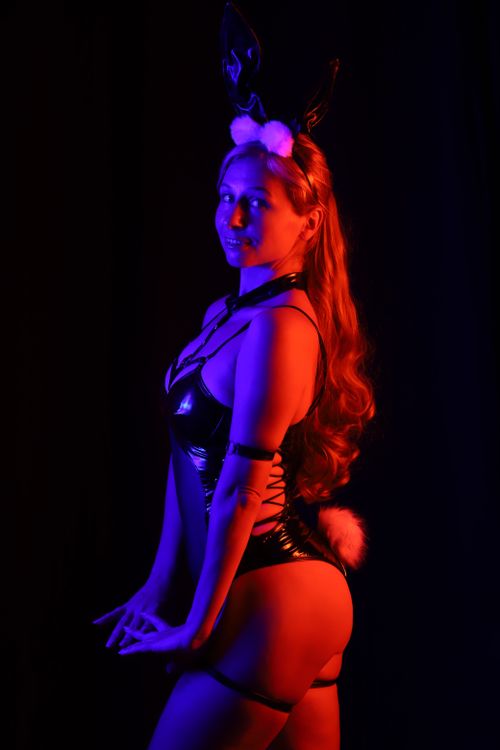 Free A stylish burlesque dancer poses under dramatic ultraviolet lighting, exuding glamour and style. Stock Photo