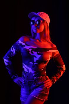 Stylish woman in camouflage outfit under dramatic UV lighting, perfect for fashion and performance themes.
