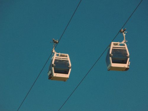 Free Two white cable cars suspended in the clear blue sky, outdoor transportation. Stock Photo