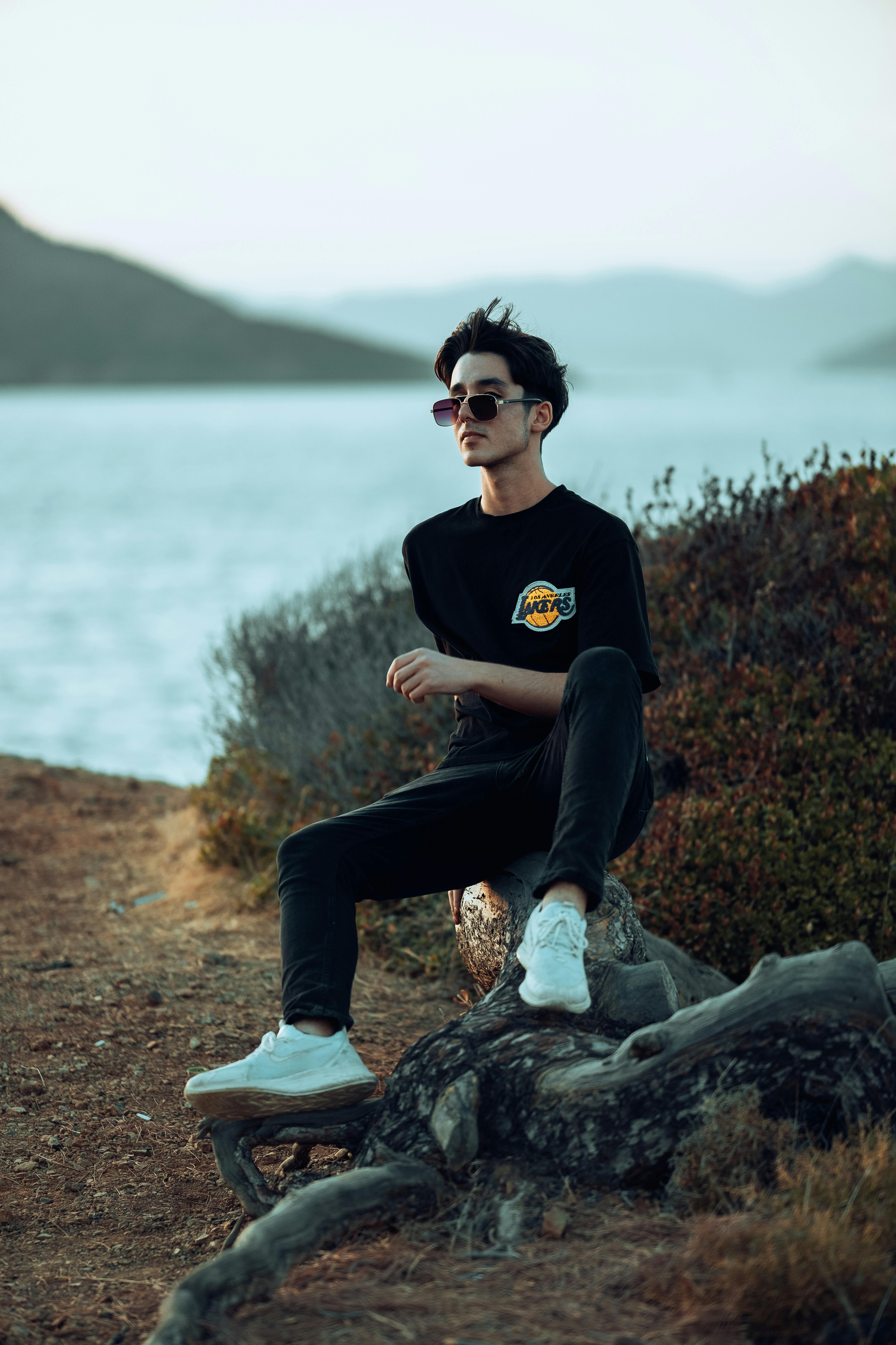 a man sitting on a tree stump near the water