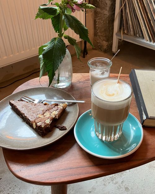 Free Cozy indoor scene with a coffee, brownie, and flowers on a table. Stock Photo