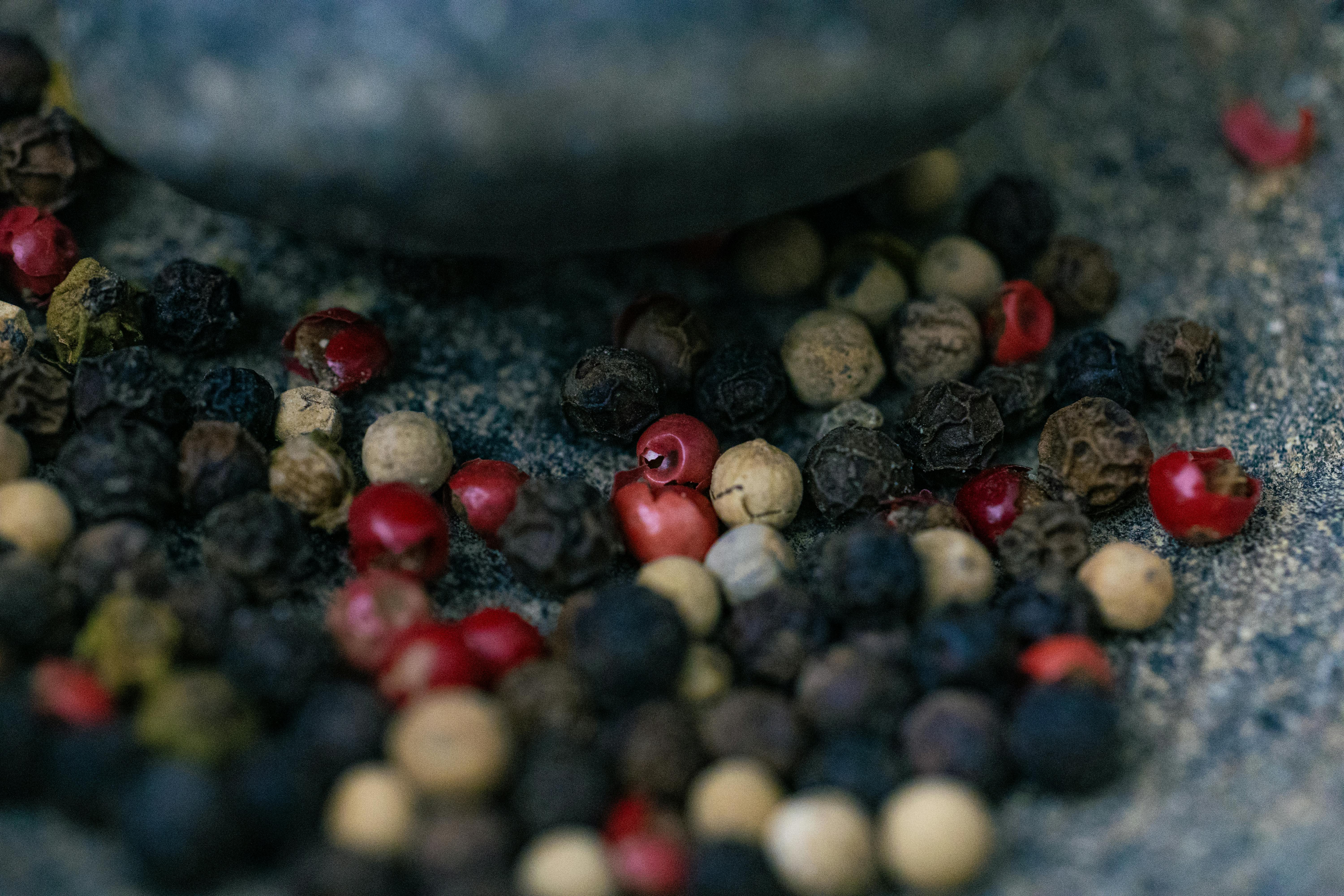 Metabolizmayı hızlandıran ve vücut ısısını artıran siyah tane karabiberler ve ahşap kaşıkta baharat görünümü.