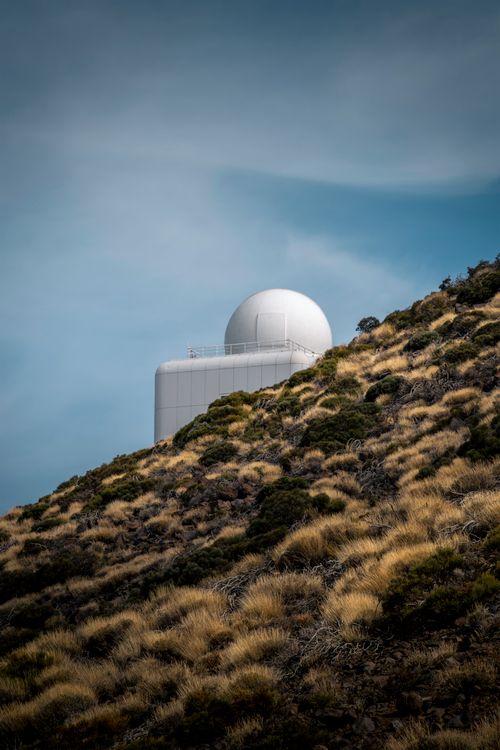Free A scenic view of an observatory atop Mount Teide surrounded by rocky landscape and under a clear blue sky. Stock Photo