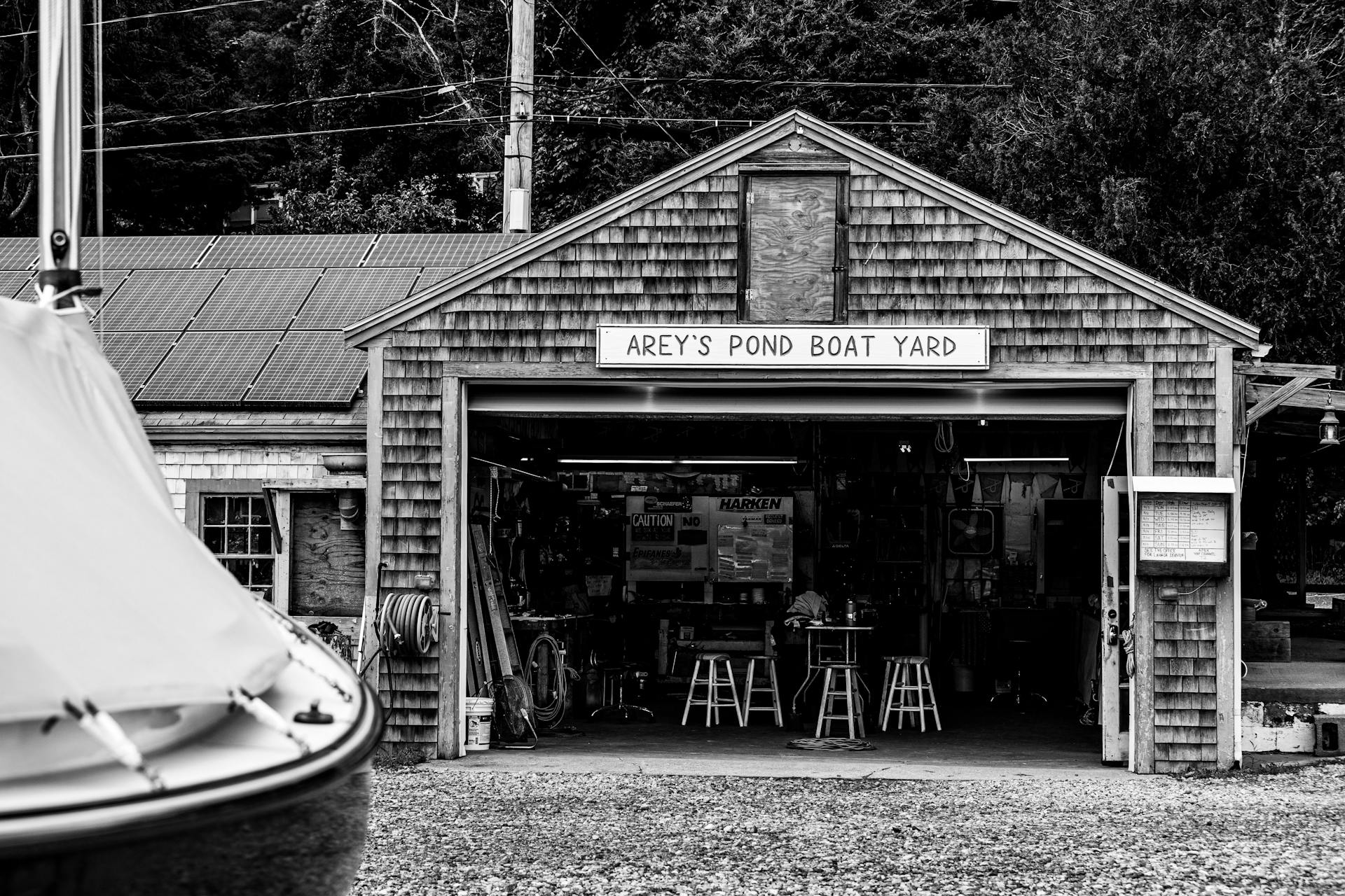 A vintage black and white view of Arey's Pond Boat Yard exterior in a quaint setting.