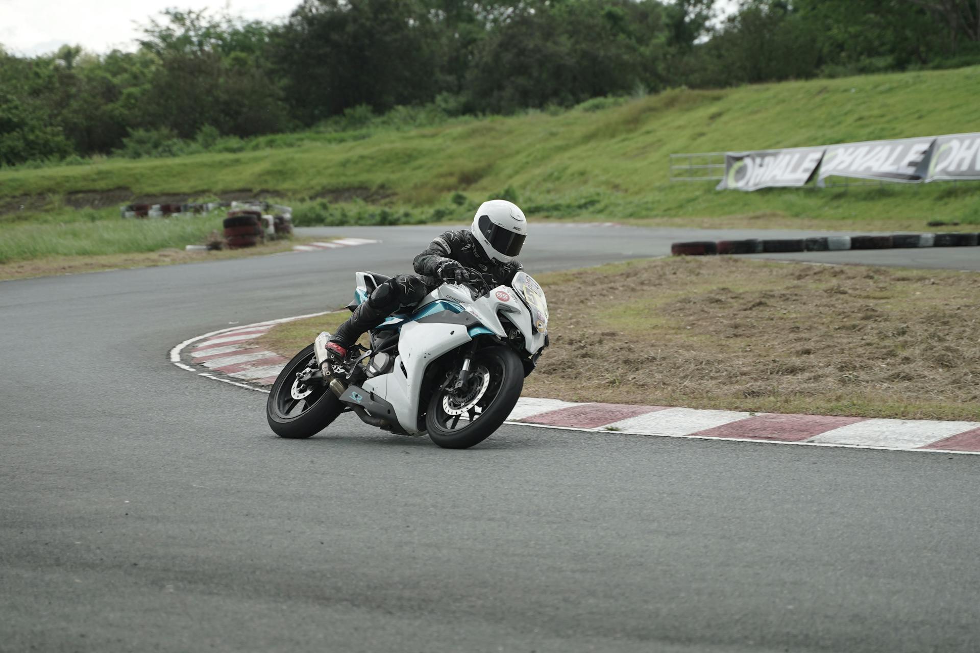 Dynamic shot of a competitive motorbike racer leaning into a sharp turn on a race track.