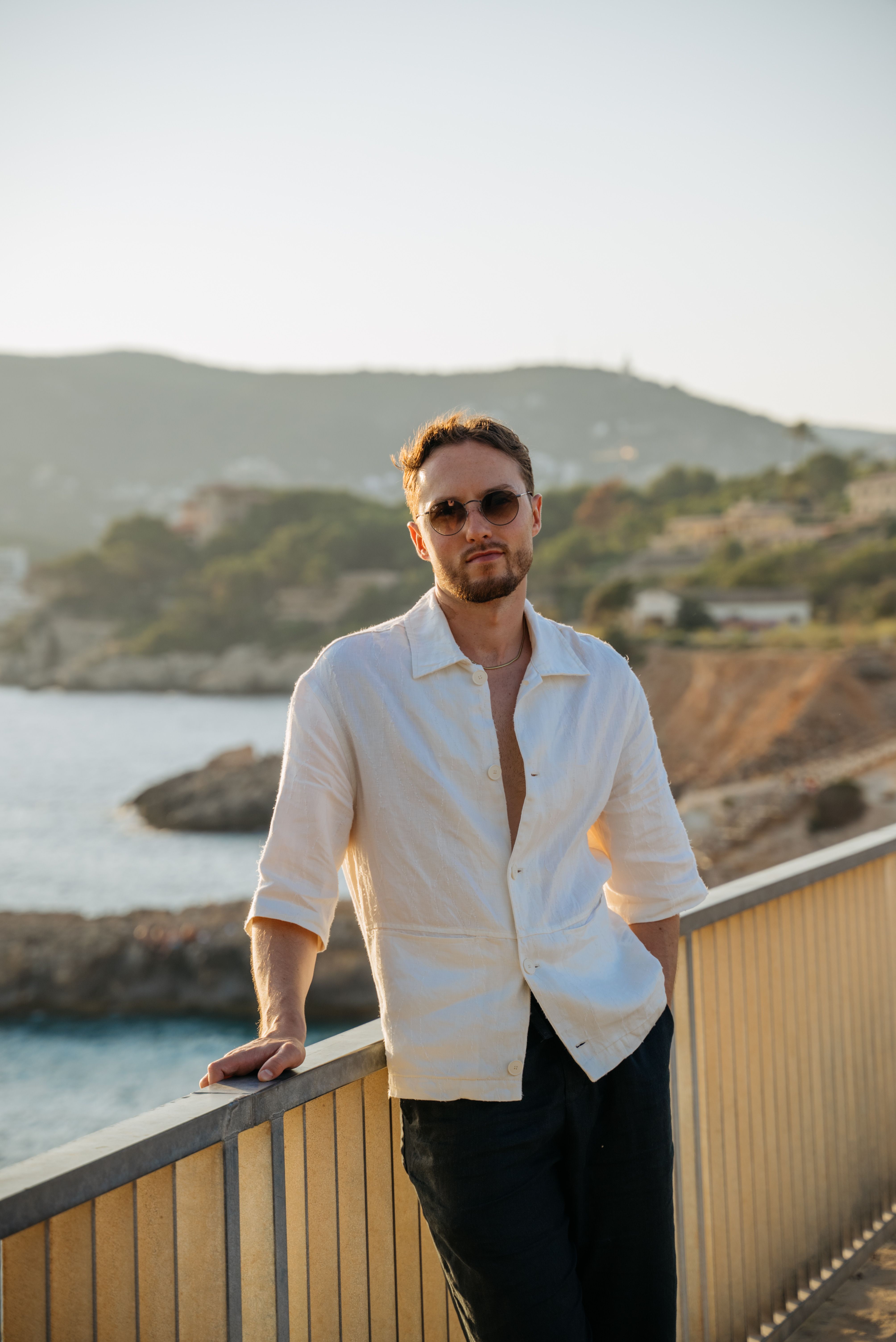 A man in a white shirt and sunglasses standing on a balcony overlooking ...
