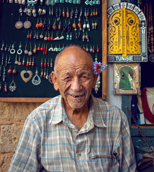 Free Portrait of an elderly Tunisian shopkeeper in a vibrant market setting in Tunis. Stock Photo