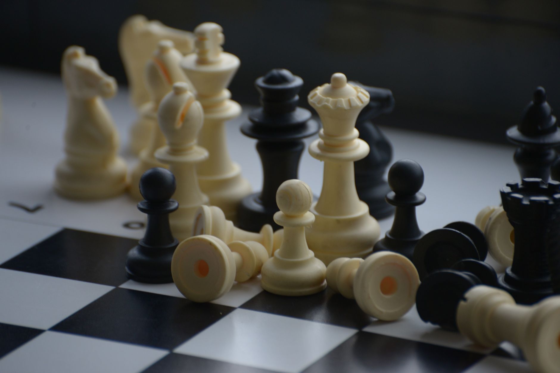 Close-up of scattered chess pieces on a black and white board.