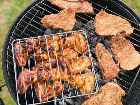 Juicy meat grilling on a charcoal barbecue outdoors, capturing summer picnic vibes.