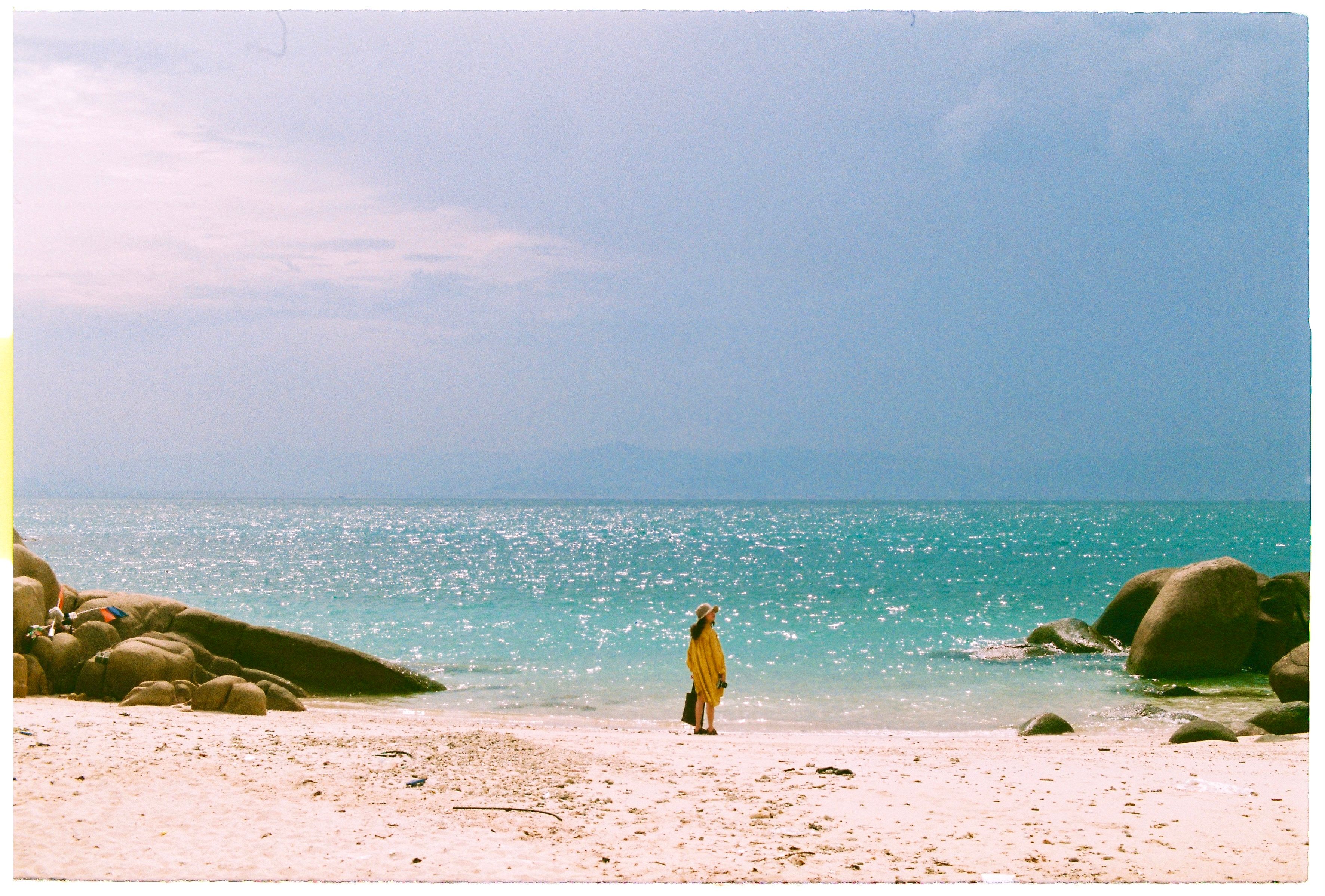 A person walking on a beach with a yellow umbrella · Free Stock Photo