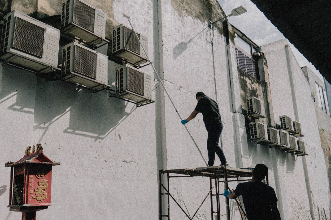 Technician on a ladder cleaning outdoor air conditioning units