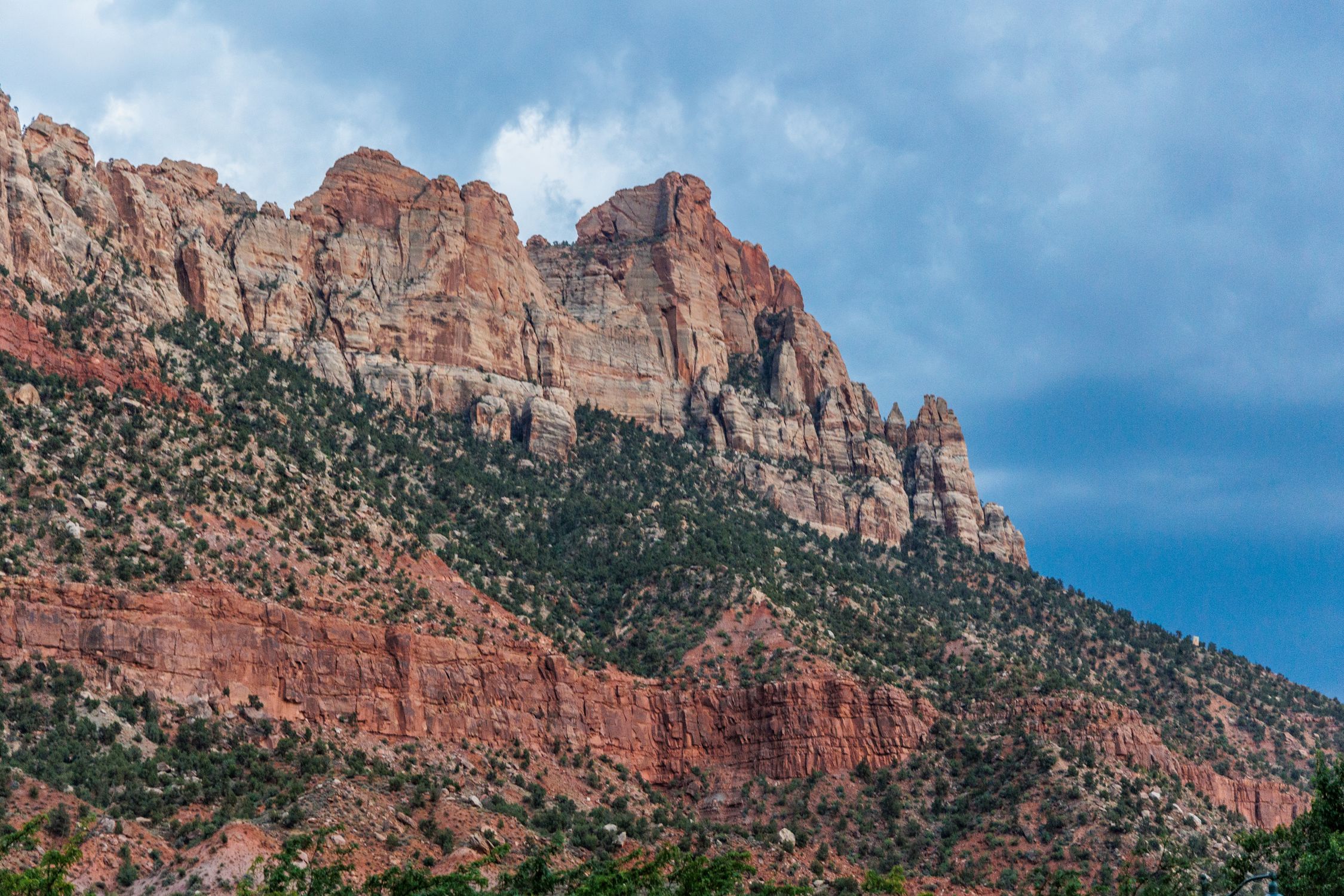 Breathtaking view of towering sandstone cliffs under a blue sky in Zion National Park, Utah.