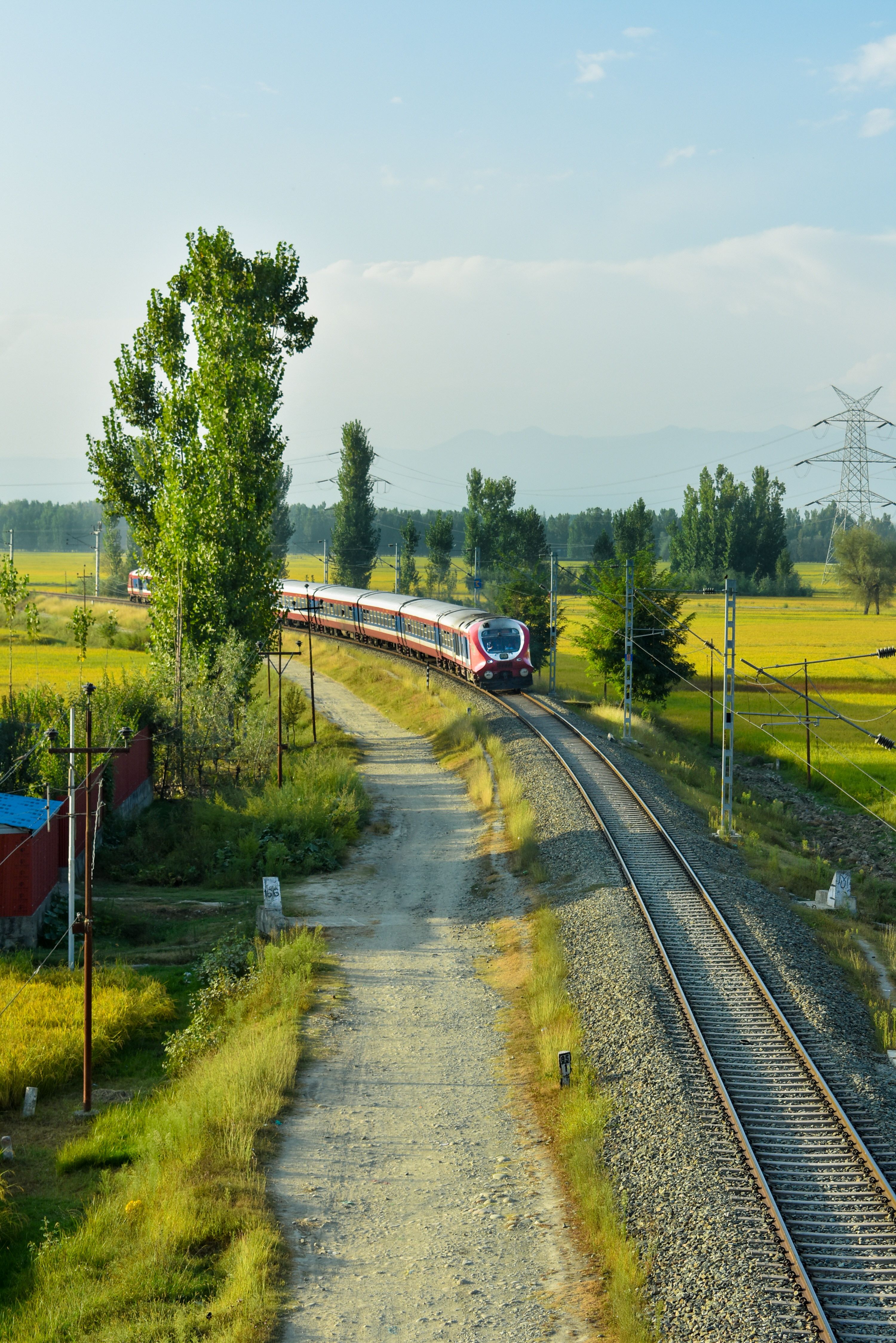 A train traveling through a rural area near a field · Free Stock Photo
