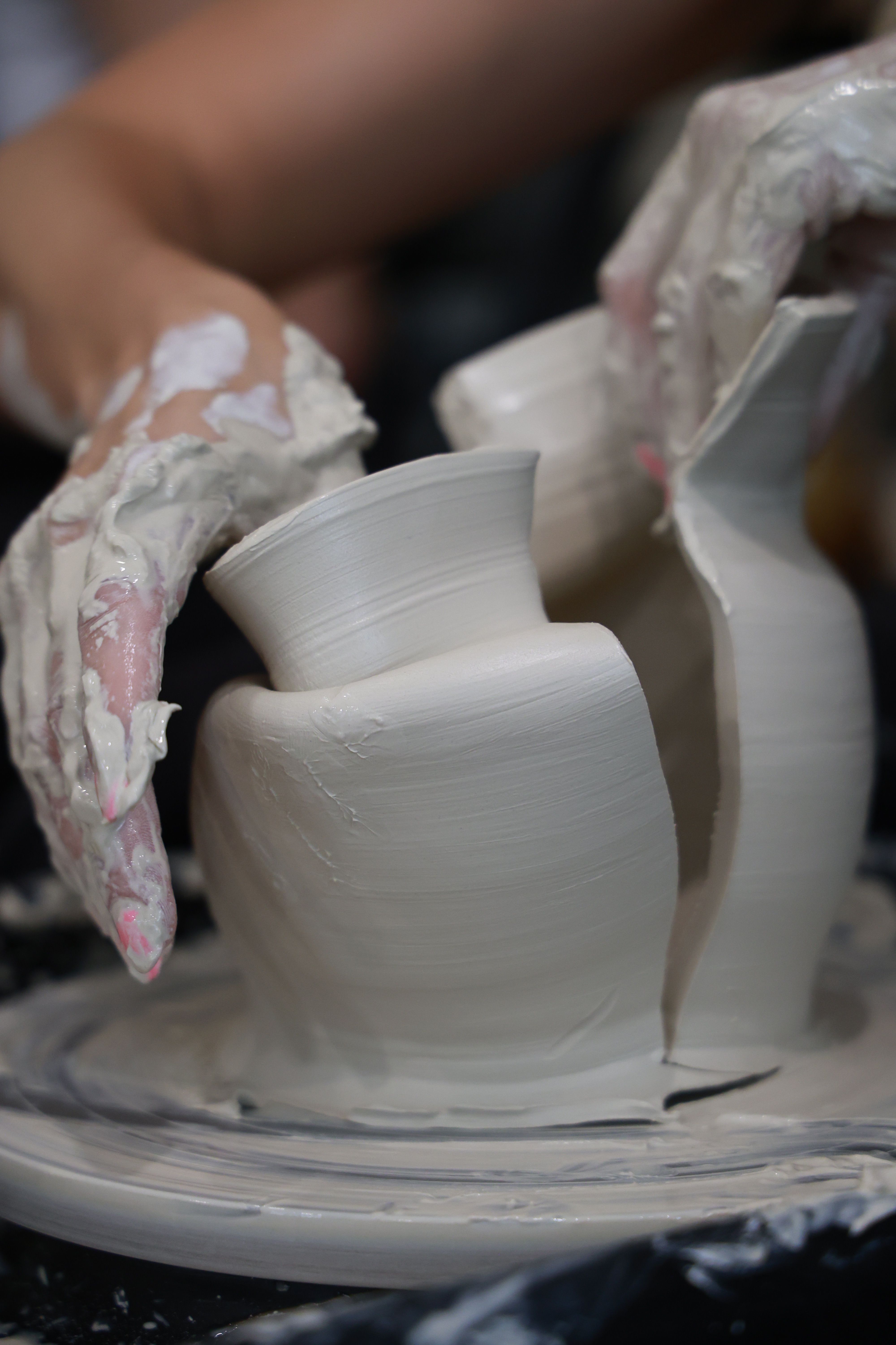 Artisan shaping clay on pottery wheel in detailed close-up view.