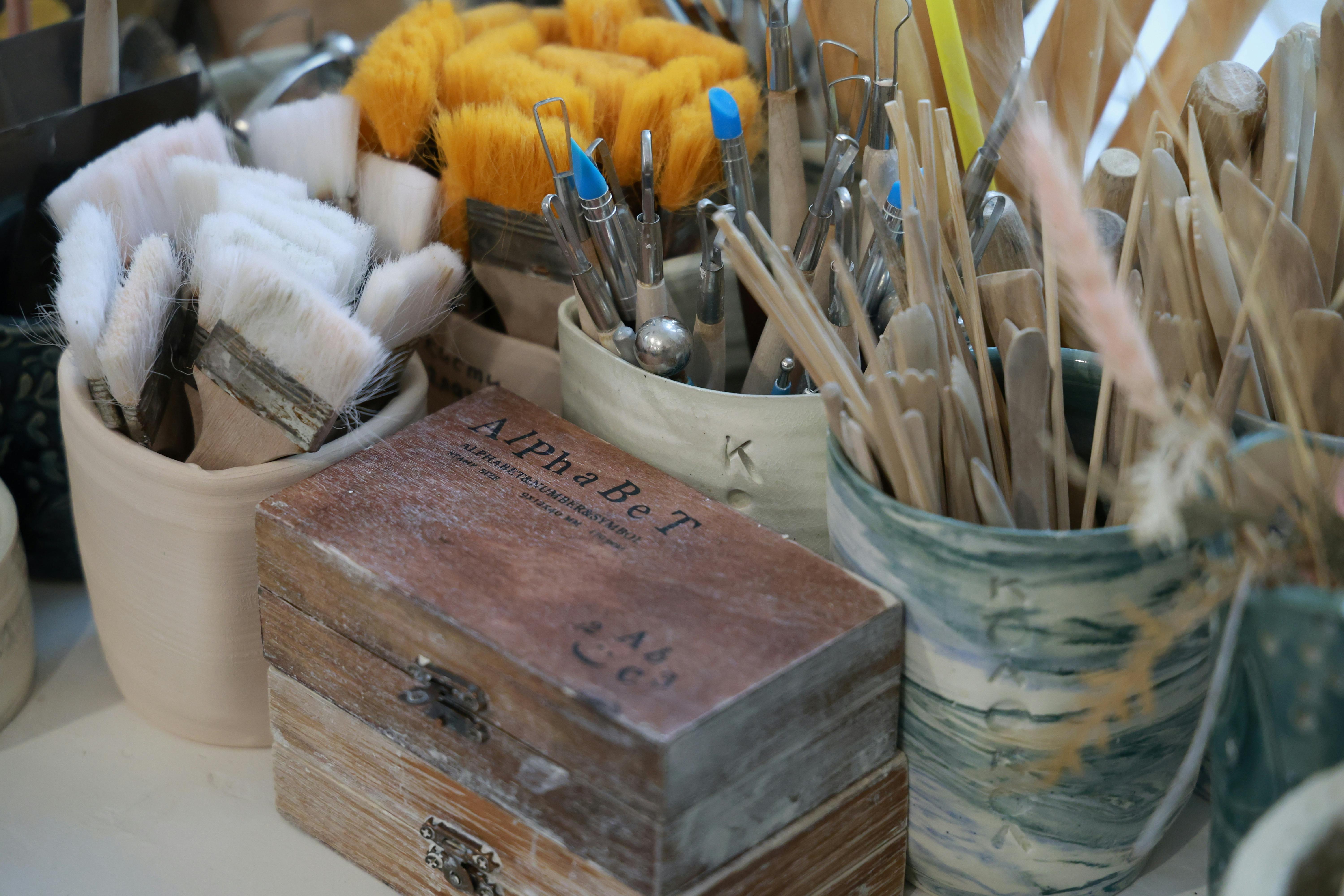 A collection of art tools including brushes and tools in rustic containers, ready for creativity.