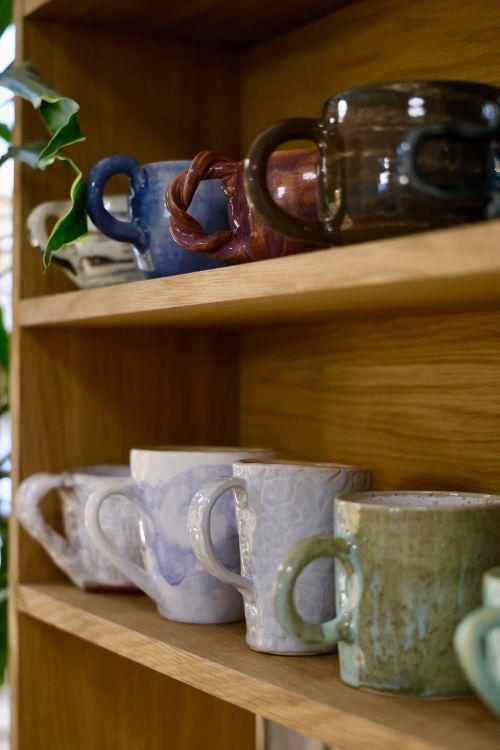 Handcrafted ceramic mugs arranged on a wooden surface — photo by Dmitry Ovsyannikov on Pexels