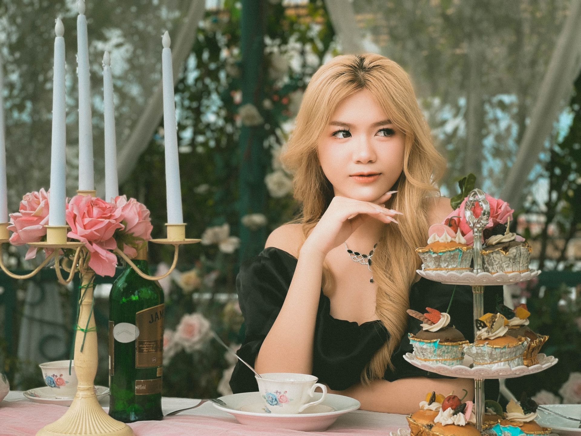 Young woman at an outdoor tea party with elegant decor, enjoying sweets and a relaxing ambiance.