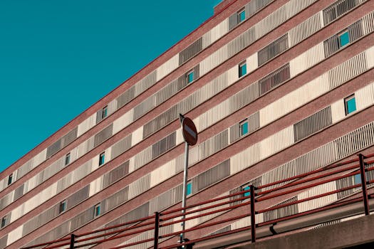 Futuristic urban building facade with striking red accents against a clear blue sky in Chamartín, Spain.